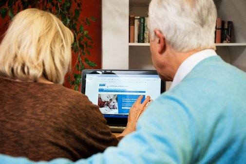 Ein älteres Paar am Computer, auf dem Bildschirm sieht man die Facebook-Seite des VdK Deutschland