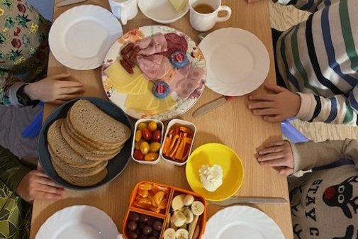 ein bunt gedeckter Fr&uuml;hst&uuml;ckstisch mit Wurst, Brot, Obst und Gem&uuml;se