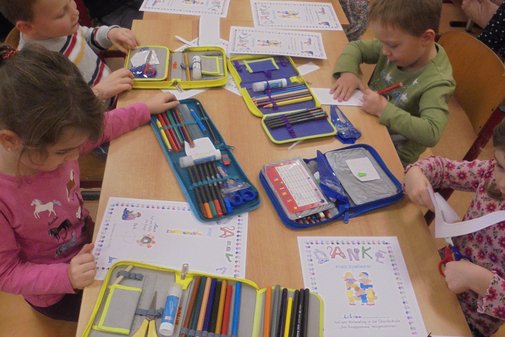 Kinder malen und basteln an einem langen Tisch