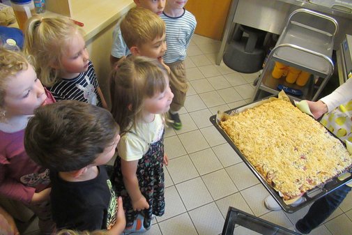 Kinder stehen um ein Blech mit Apfelkuchen