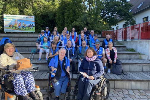 viele Personen mit blauen Warnwesten sitzen nebeneinander