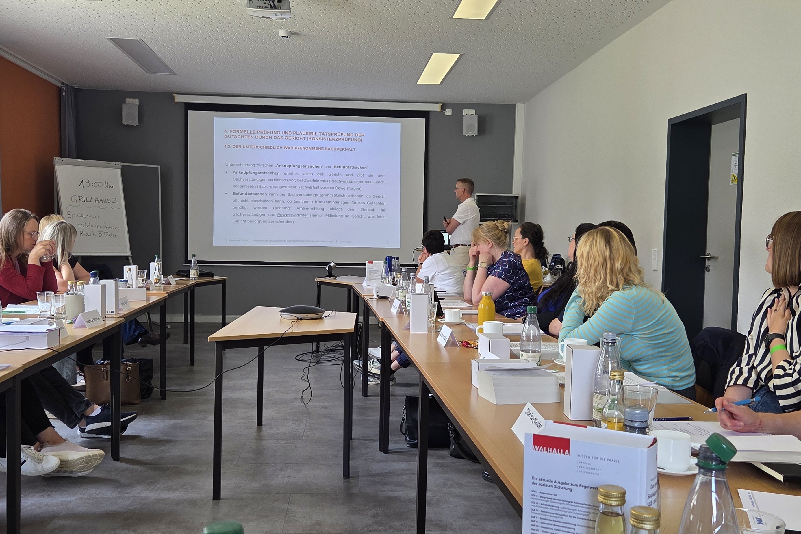 Blick in einen Seminarraum, in dem viele Personen an Tischen sitzen