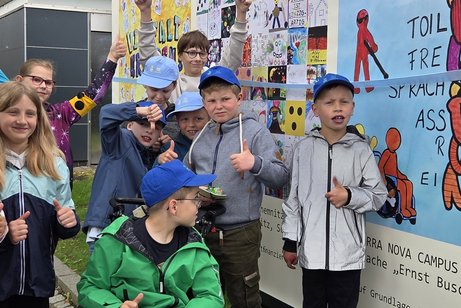 viele Kinder stehen vor einem bunten Plakat