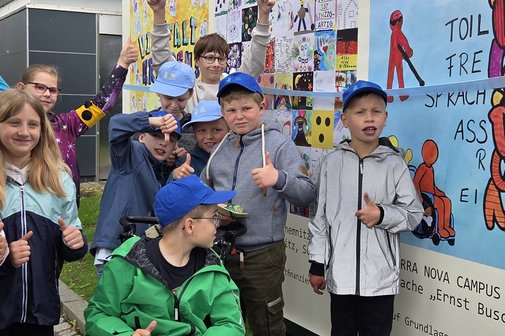 viele Kinder stehen vor einem bunten Plakat