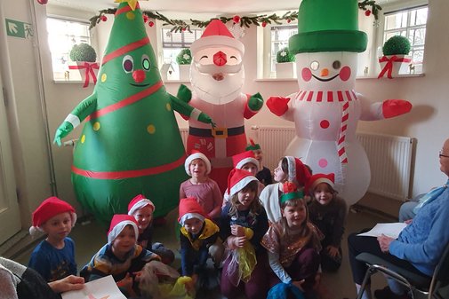 eine Gruppe Kinder sitzt vor lustigen Aufblasfiguren