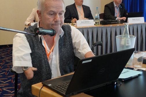 Mann mit Laptop liest etwas vor.