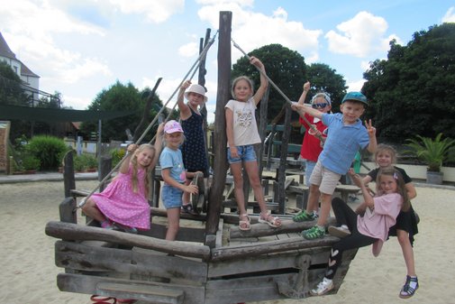 mehrere Kinder sitzen und stehen auf einem Klettergerüst
