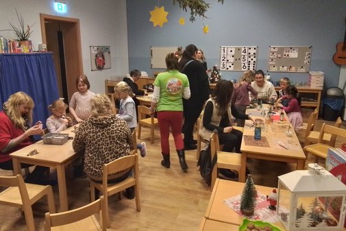 in einem Raum sitzen Erwachsene und Kinder an verschiedenen Tischen, es wird gebastelt