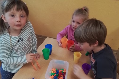 drei Kinder spielen an einem Tisch