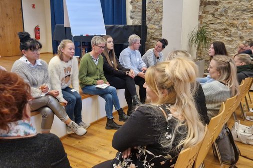 eine Gruppe von Frauen sitzt im Kreis und ber&auml;t sich