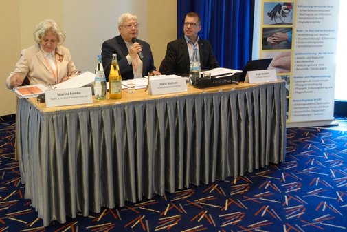 zwei Männer und eine Frau sitzen nebeneinander an einem Tisch