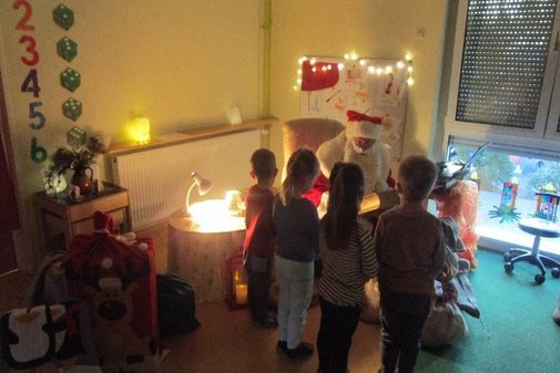 mehrere Kinder stehen vor einem Weihnachtsmann