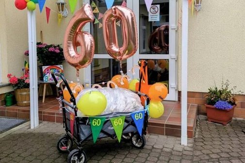 ein Bollerwagen geschmückt, unter anderem mit einer großen Luftballonzahl 60
