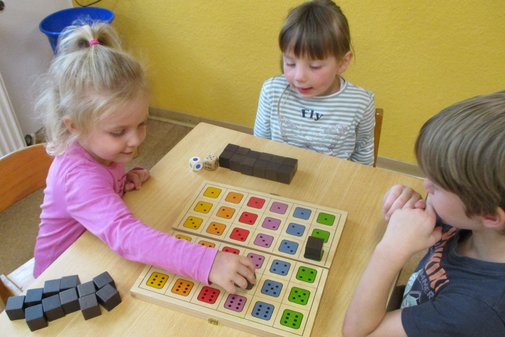 drei Kinder spielen ein Würfelspiel