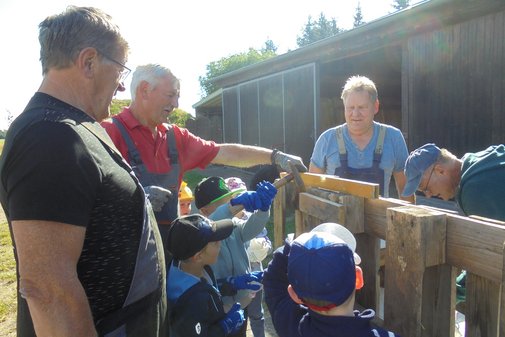 Kinder und Senioren stehen um eine selbst gebaute Kinderküche