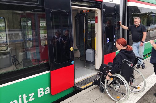 Frau im Rollstuhl steht an einem Bahnsteig