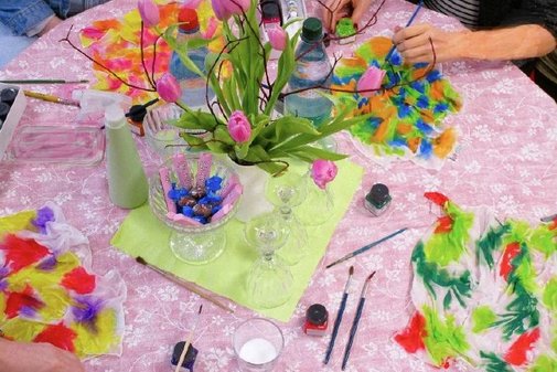 bunte T&uuml;cher liegen auf einem Tisch und werden bemalt