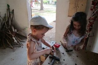 Zwei Kinder hantieren in einer Holzwerstatt mit einem Hammer