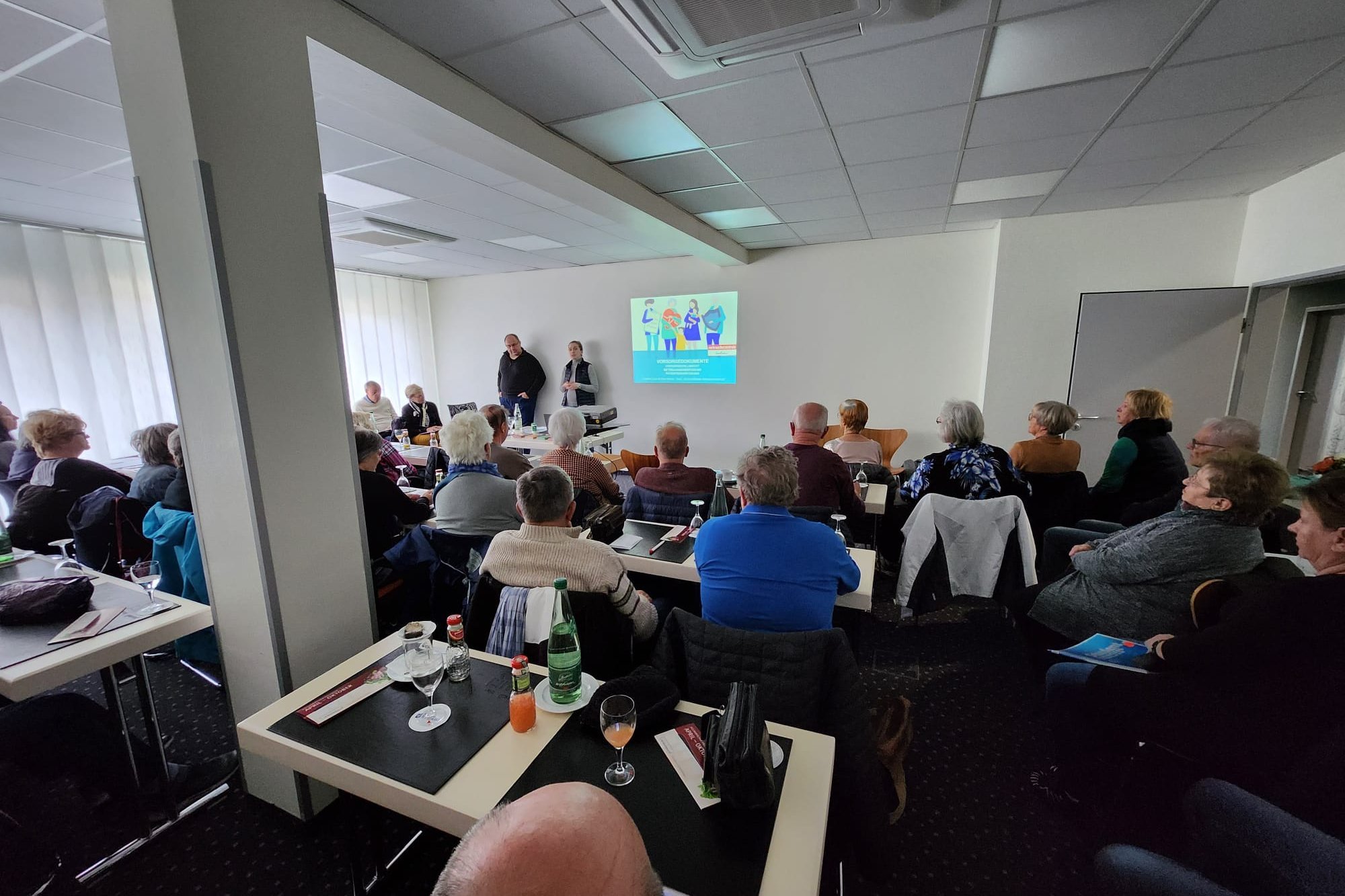 Blick in einen Veranstaltungsraum, in dem viele Menschen sitzen