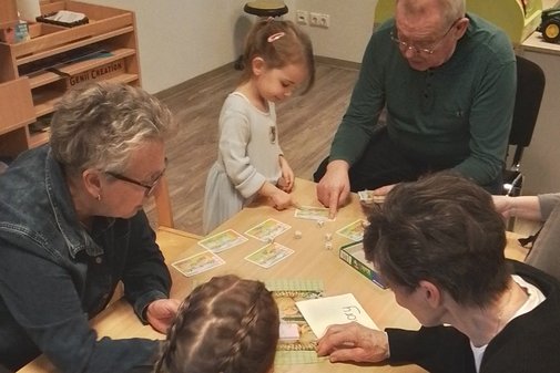 Omas, Opas und Kinder sitzen an einem Tisch und basteln