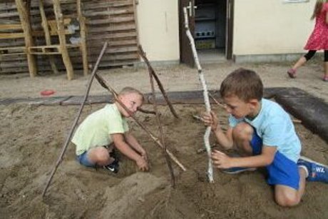 Kinder spielen mit Naturmaterialien im Sandkasten