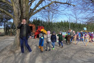 ein Mann und mehrere Kinder laufen über einen Spielplatz