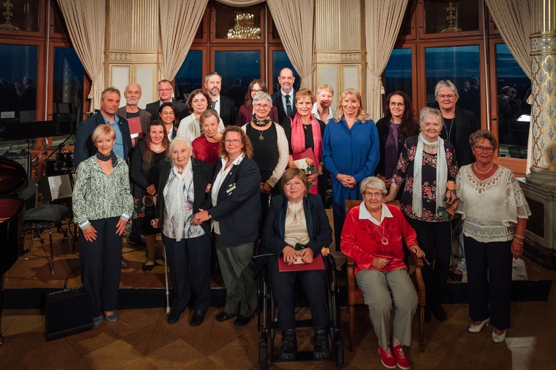 eine größere Gruppe von Personen lächelt in die Kamera