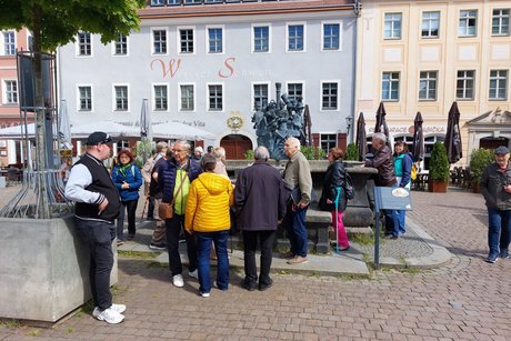 Gruppe von Teilnehmern bei der Besichtigung des Brunnens auf dem Marktplatz in Pirna