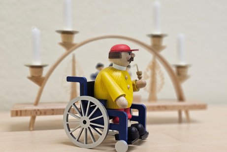 R&auml;uchermann im Rollstuhl vor einem Schwibbogen