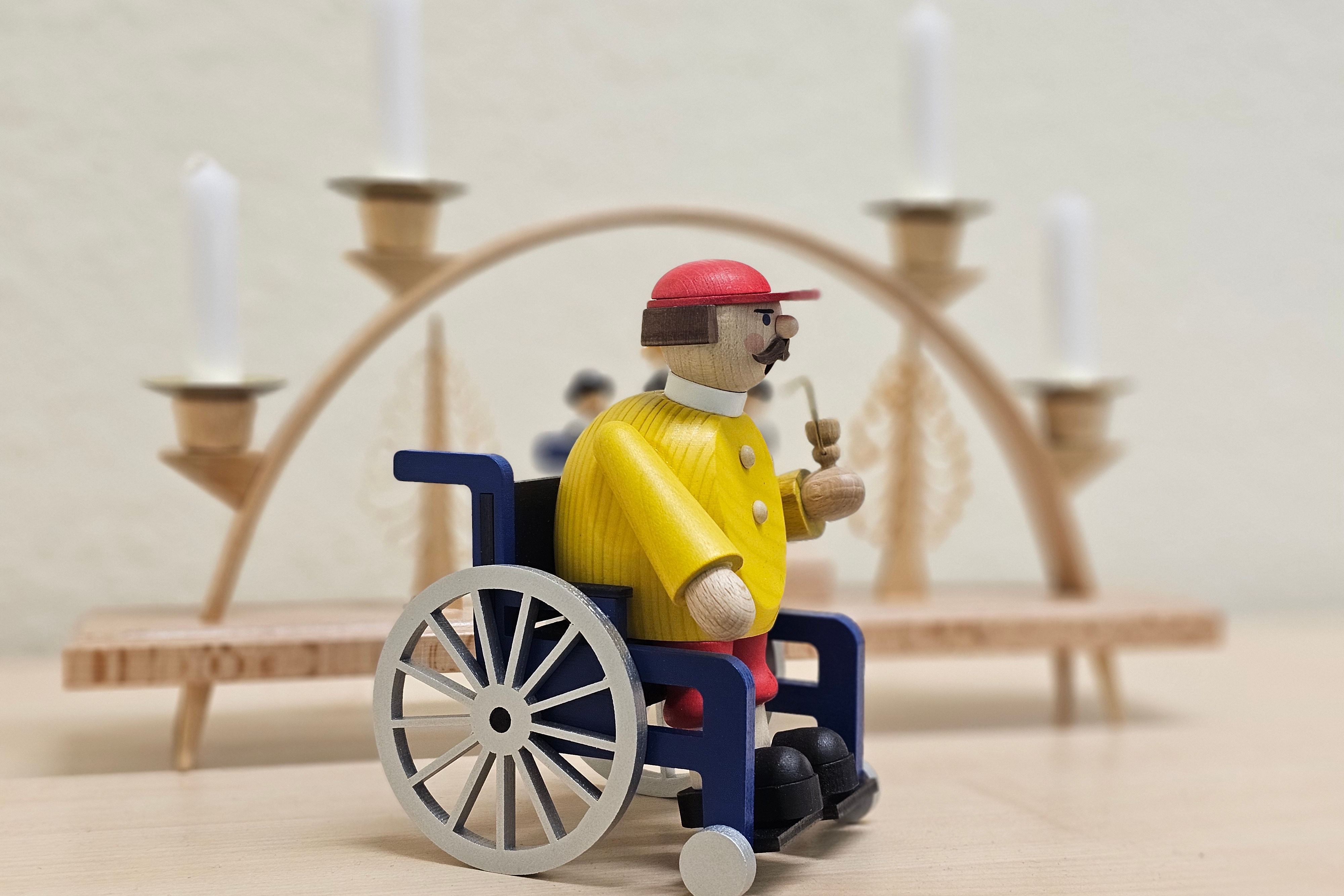 R&auml;uchermann im Rollstuhl vor einem Schwibbogen